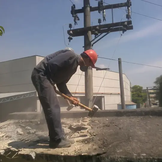 Profissional executando demolição manual com EPI em obra em Cotia/SP
